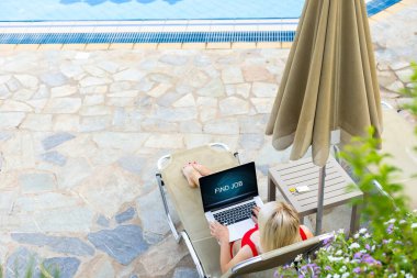 güneşlenme havuzu tarafından üzerinde rahatlatıcı iken dizüstü bilgisayar kullanan kadın