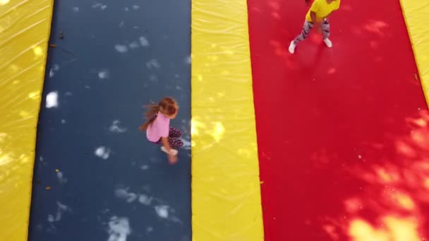 Two little girls in the summer jump on a trampoline, smiling and laughing. Children play. Relax in the fresh air. Friends jump on a trampoline. Happy child — Stock Video