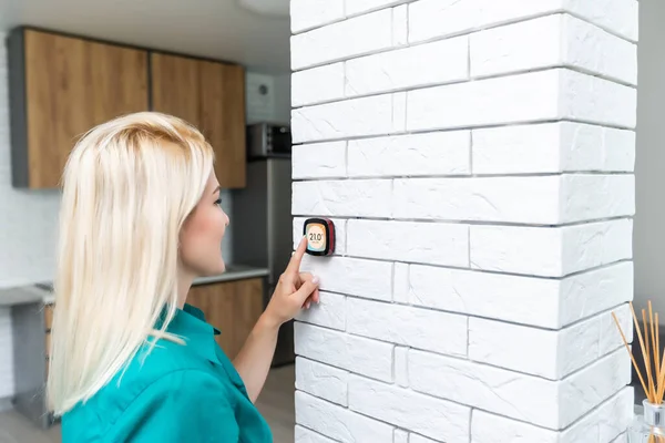 Lächelnde Frau justiert Thermostat an Heizungsanlage — Stockfoto