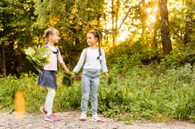Parkta iki kız eğleniyor, sonbahar kıyafeti. Sonbaharda şehre yapraklar atan komik kız arkadaşlar. Sonbahar yürüyüşünde mutlu bir aile. Jest barışı.