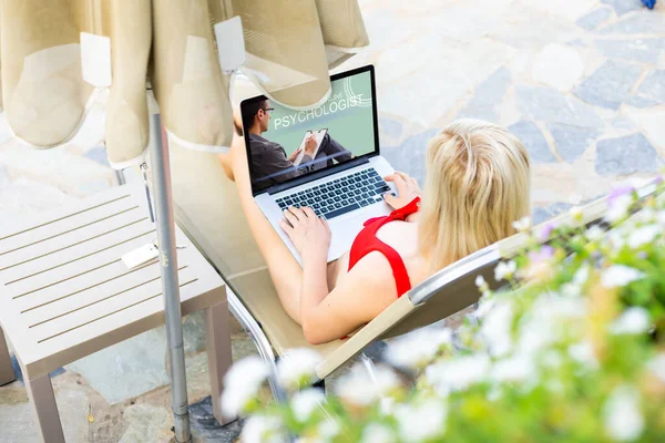Freelancer mulher, blogueiro de viagens trabalha em um laptop. sentado em uma espreguiçadeira no jardim junto à piscina . — Fotografia de Stock