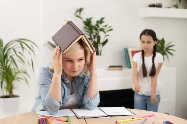 Güzel liseli kız annesiyle evde ödev yapıyor.