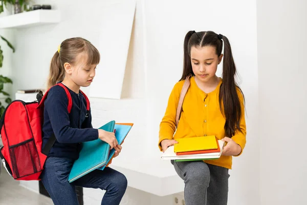Две маленькие школьницы разговаривают и делятся секретами. Образование, мода, дружба. — стоковое фото