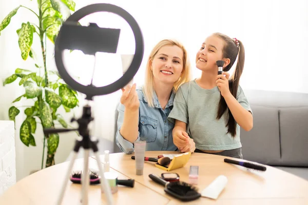 Famous blogger concept. Cheerful Mother and daughter blogger is showing cosmetics products while recording video with camera and giving advice for her beauty blog. — Stock Photo, Image