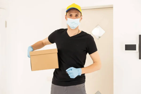 Homem de entrega segurando pacote para entregar. Courier mão segurando caixa marrom isolado em fundo cinza. Detalhe do entregador transportando pacote de papelão com etiqueta com espaço de cópia. — Fotografia de Stock