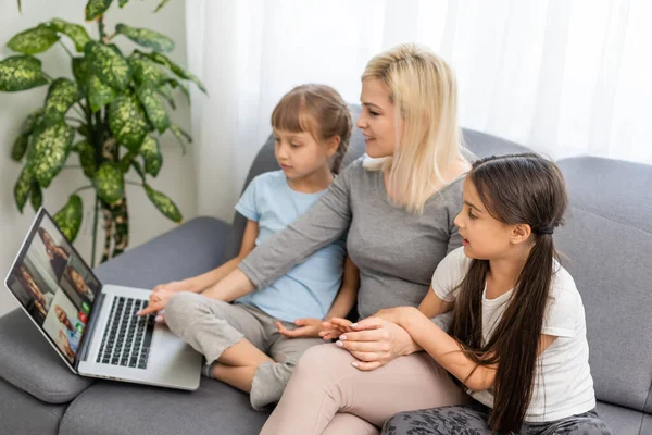 Mãe sorridente com crianças pequenas usando laptop em casa — Fotografia de Stock