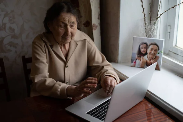 Hyvin vanha nainen käyttää kannettavaa tietokonetta istuu kotona — kuvapankkivalokuva