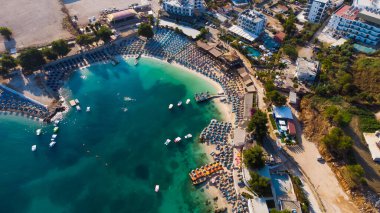 Arnavutluk 'un güzel Ksamil plajında güneşlik şemsiyeler ve şezlonglar.