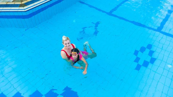 Mãe e filha brincando em uma piscina — Fotografia de Stock