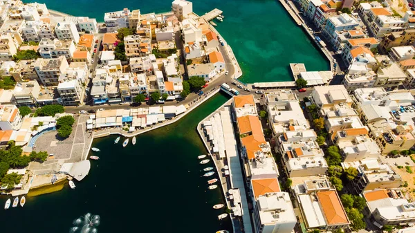Agios Nikolaos. Kreta. Griechenland. Gebäude am Ufer des Sees Voulismeni und Boote an der Seebrücke — Stockfoto