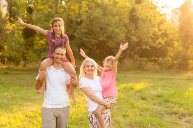 Mutlu aile tarlada yürüyor ve gün batımını seyrediyor.
