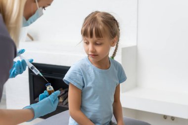 Küçük kız muayenehanedeki çocuk doktorundan aşı oluyor.