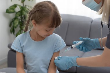Küçük kız muayenehanedeki çocuk doktorundan aşı oluyor.