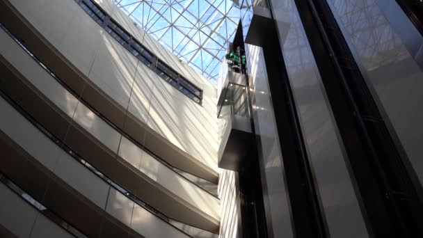Кілька поверхів великого сучасного бізнес-центру з відкритими офісами, вікнами, балконами та ліфтом між ними — стокове відео