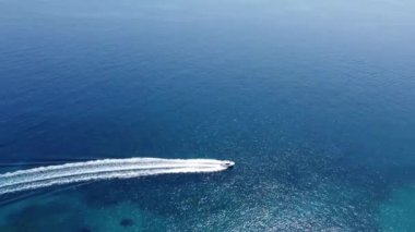 Parasailing, Parasailing Bir Teknenin Arkasında. Adam bir paraşütle denizin üzerinde uçuyor. Dağın arka planındaki tekneye bir ip bağlıyor.