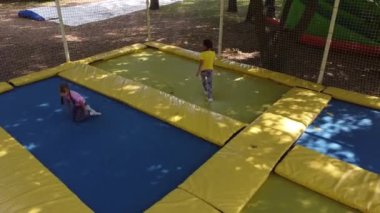 Küçük güzel kızlar açık eğleniyor. Çocuk bölgedeki trambolin üzerinde atlama. Eğlence Parkı