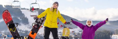 Anne ve kızı kış tatilinde snowboard yapıyor.