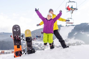 Bir dağ evinde snowboard yapan anne ve kız.