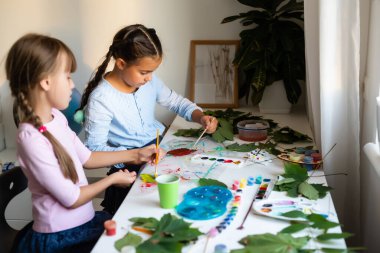 Çocuklar için sonbahar sanatı. Akçaağaç yaprağından yapılmış hayvan tilkisi. Çocuk sanatı ve yaratıcı. Doğal malzemelerden yapılmış el işi. Kızlar boyayla resim yapar..