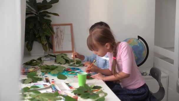 Két iskoláslány festi a leveleket. — Stock videók