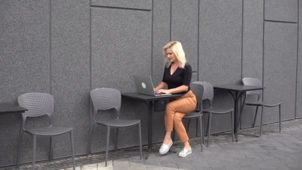 Молодая деловая женщина, работающая за компьютером в кафе. Молодая девушка дауншифтер работает за ноутбуком, рабочий день. — стоковое видео