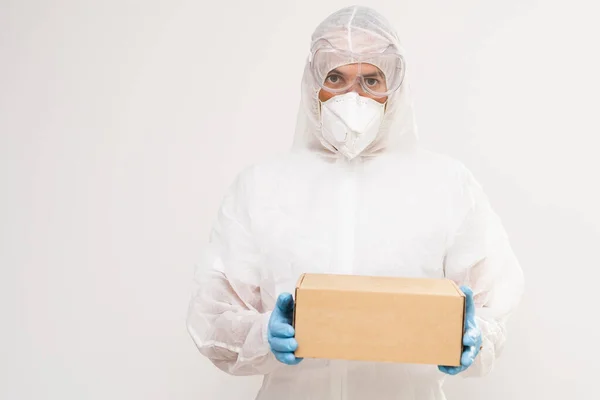 Homem de pé isolado contra o fundo branco em um terno hazmat com uma parcela em suas mãos — Fotografia de Stock