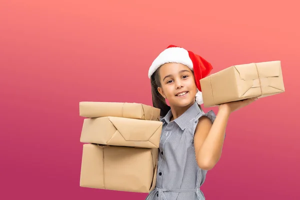 Малу дитину, яка тримає велику кількість різдвяних подарунків, ізольовану на рожевому капелюсі.. — стокове фото