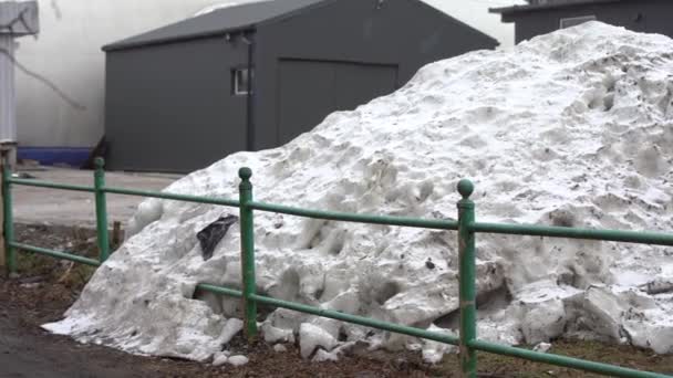 As montanhas de neve suja na cidade são coletadas por equipamentos de remoção de neve perto das estradas após a queda de neve anômala no inverno — Vídeo de Stock