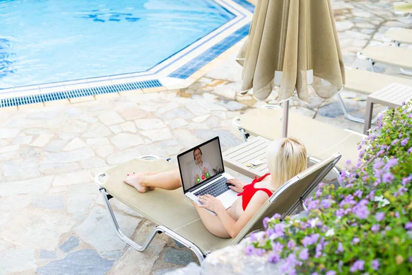 Woman Using Laptop Whilst Relaxing On Sun Lounger By Pool — Stock Photo, Image