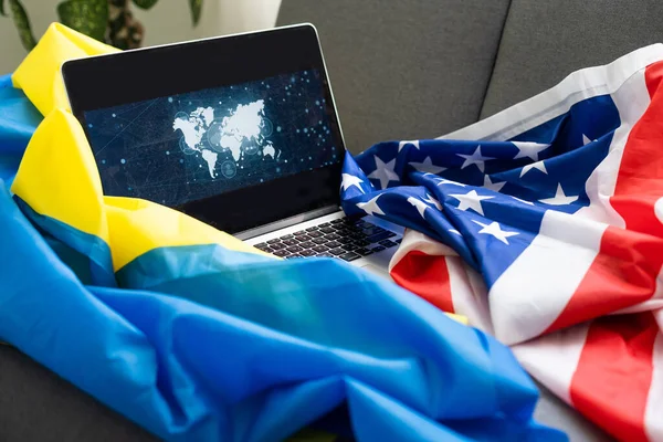Ноутбук рядом с Америкой и флагом Украины. — стоковое фото