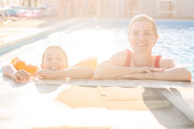 Anne ve kızı yüzme havuzunda oynuyorlar.