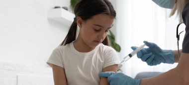 Hemşire küçük kız hastaya aşı yapıyor.