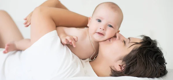 Mutlu bir aile. Anne ve bebek yatakta oynuyor ve gülümsüyor. — Stok fotoğraf