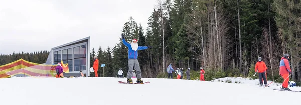 Glad man i Santa röd jul hatt med snowboard på vintern berg kulle — Stockfoto