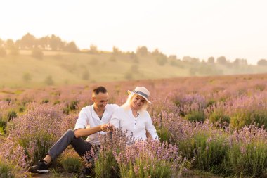 Gülümseyen genç çift lavanta tarlasında el ele tutuşuyorlar, yürüyorlar..