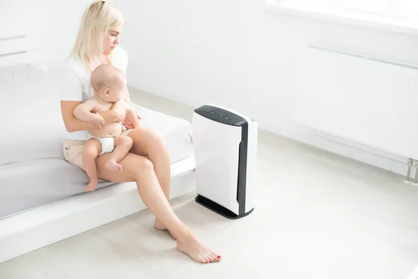 Mother and baby near air purifier at home — Stock Photo, Image