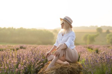 Lavanta tarlasında duran genç bir kadın ve arka planda gün doğumu.