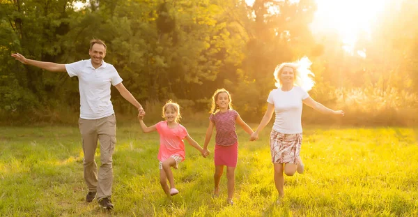 Famille heureuse profitant de la vie ensemble au pré en plein air. — Photo