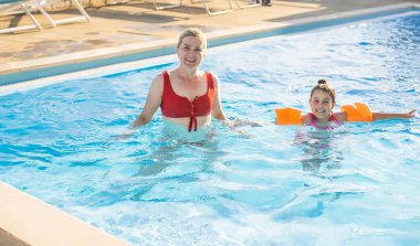 Mutlu anne ve kız eğlence merkezindeki yüzme havuzunda.