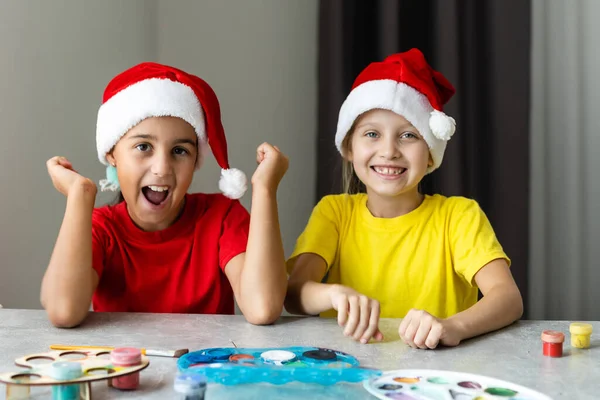 Mutlu çocuklar Noel kartı yapıyor Noel Baba şapkası takıyor. — Stok fotoğraf