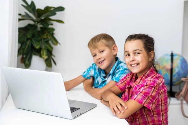 Симпатичные дети используют ноутбук для обучения, онлайн-обучения, домашнего обучения, у мальчиков и девочек есть домашняя работа на дистанционном обучении. Концепция стиля жизни для домашнего обучения. — стоковое фото