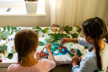 İki liseli kız yaprak çizer, kızlar sonbahar yapraklarını boyarlar