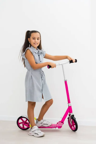 Schattig klein meisje met een scooter. Geïsoleerd op witte achtergrond — Stockfoto