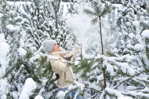 Ein Mädchen in weißen Kleidern steht neben einer Kiefer im Schnee. — Stockfoto