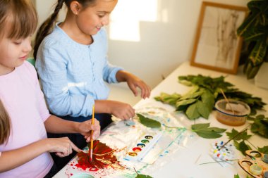 İki liseli kız yaprakları boyuyor.