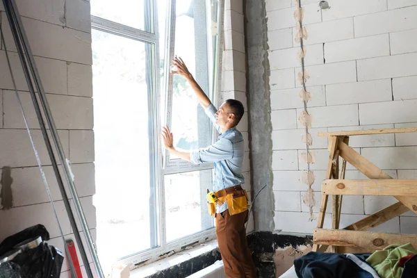 Будівельник встановлює вікно в будинку — стокове фото