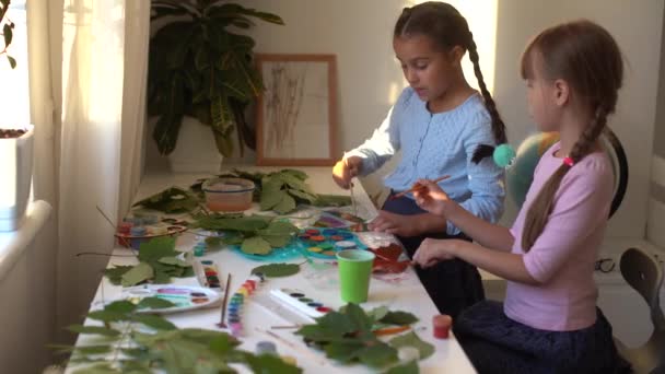 Dos colegialas dibujan hojas, las niñas pintan hojas de otoño — Vídeos de Stock