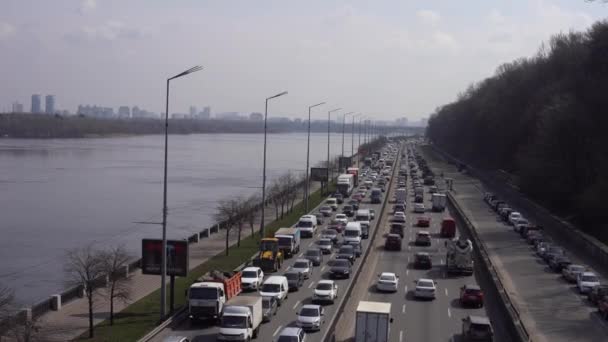 Ukrayna, Kiev - 6 Nisan 2021. Ukrayna 'nın Kiev kentindeki otoyol kenarından arabalar geçiyor. Yoğun bir yolda iki yönde de trafik vardı. Şehir manzarasının havadan görüntüsü. — Stok video