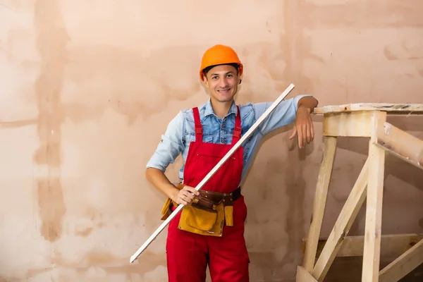 Repair, building, construction, people and maintenance concept - smiling man with helmet over wall background — Stock Photo, Image