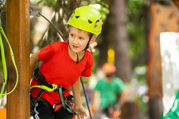 Cute school boy enjoying a sunny day in a climbing adventure activity park — Stock Photo, Image